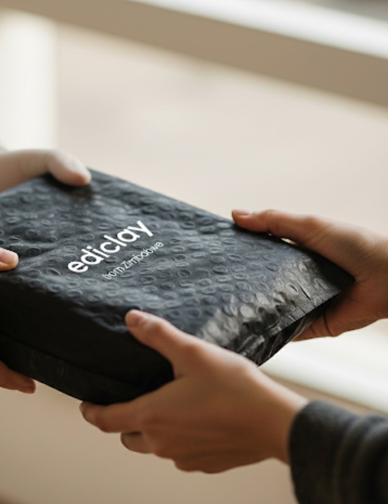 Person holding a black box with 'ediclay' branding.